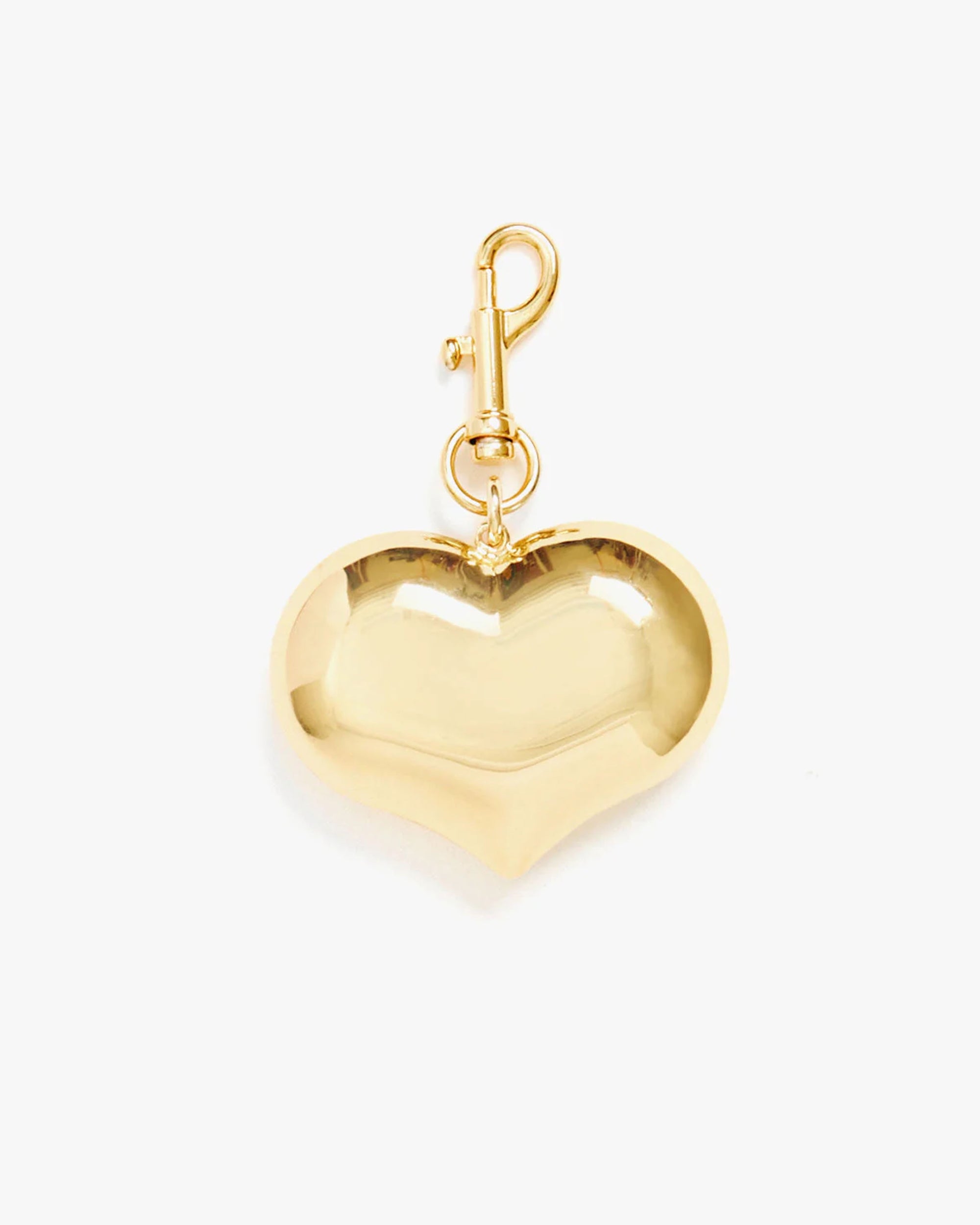 The Clare Vivier Grand Mylar Heart FOB, a gold heart-shaped charm with a shiny surface and top clasp, is perfect as a keychain or elegant bag accessory, displayed against a plain white background.