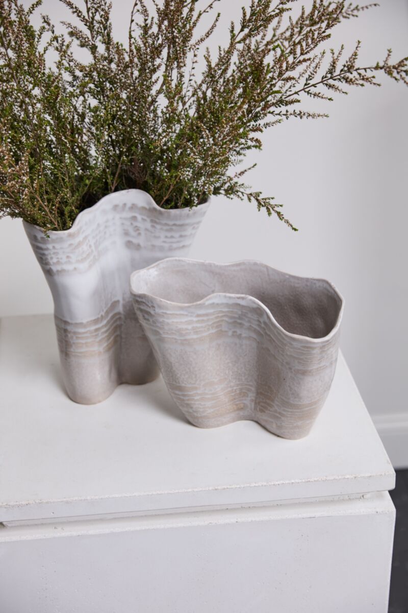Wavy beige and white Claribel Vase Short by Accent Decor with green branches on a white tabletop.