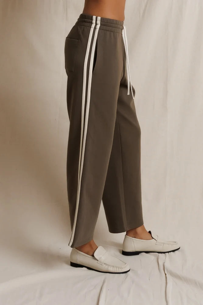 Perfectwhitetee Claud Track Pant styled with white loafers, shown against a soft cream fabric backdrop.