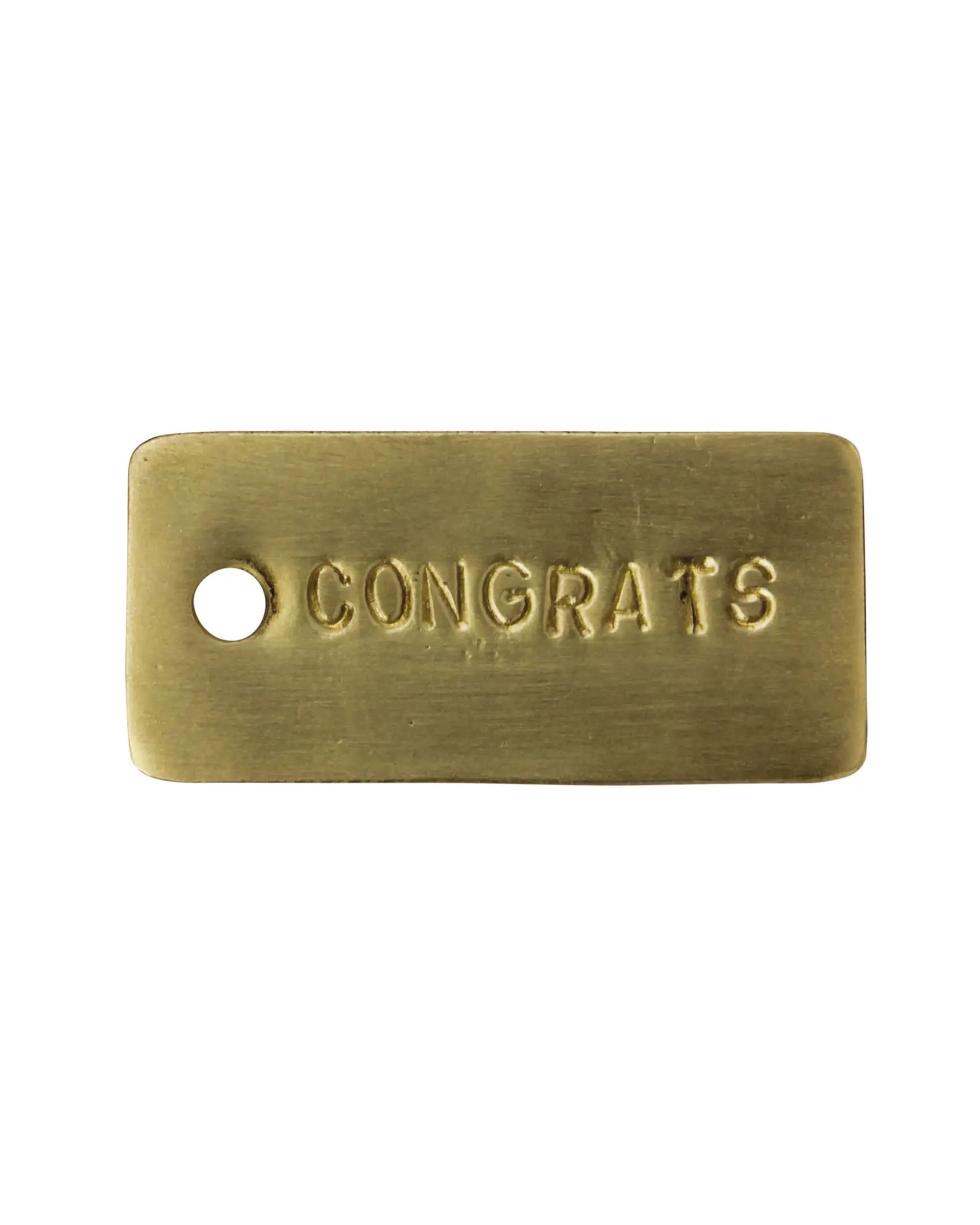 The HomArt Brass Tag is a rectangular hand-stamped brass gift tag with rounded edges, "CONGRATS" in uppercase, and a small left-side hole—ideal for adding a sentimental touch to your gift.