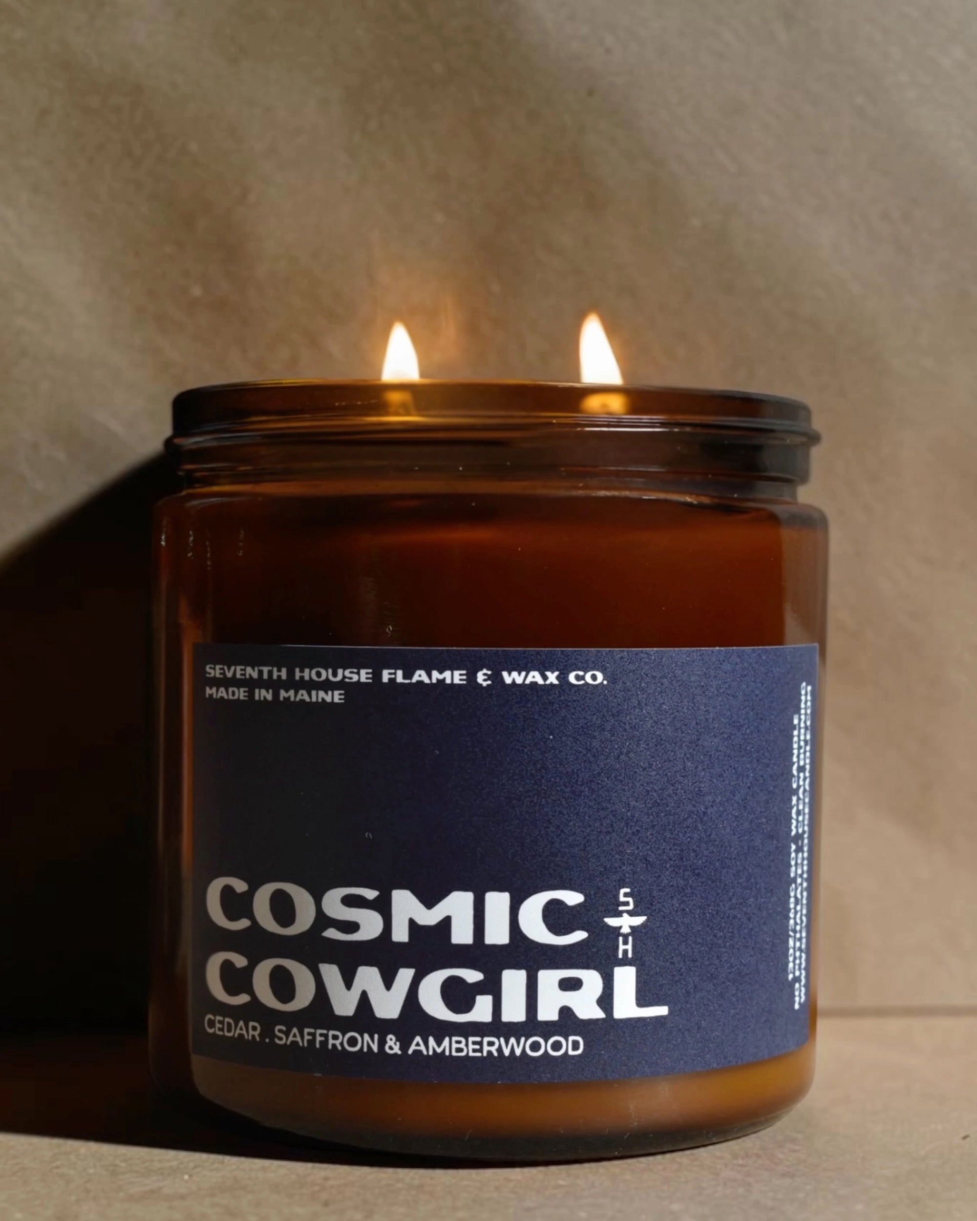 Brown soy coconut wax candle with dual wicks in a jar, Faire Cosmic Cowgirl Collection, softly glowing.
