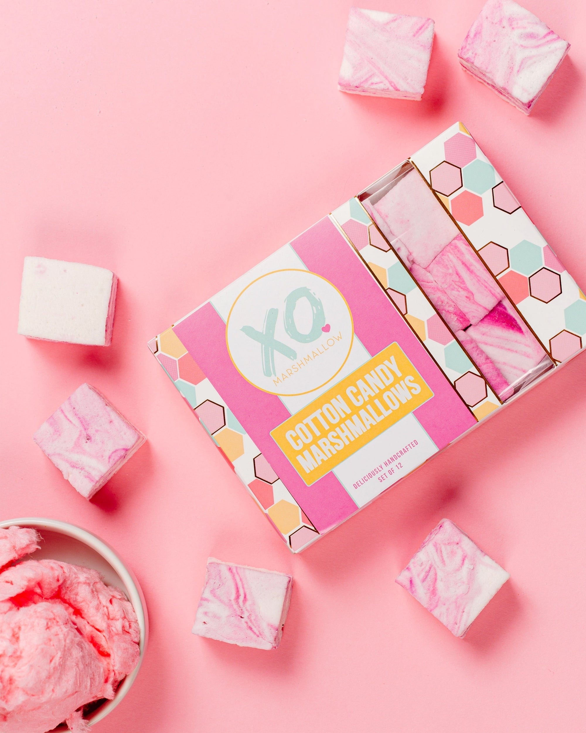A box of Faire Cotton Candy Marshmallows, naturally colored and allergy friendly, is displayed on a pink background with pink and white swirled marshmallows and a bowl of pink ice cream.