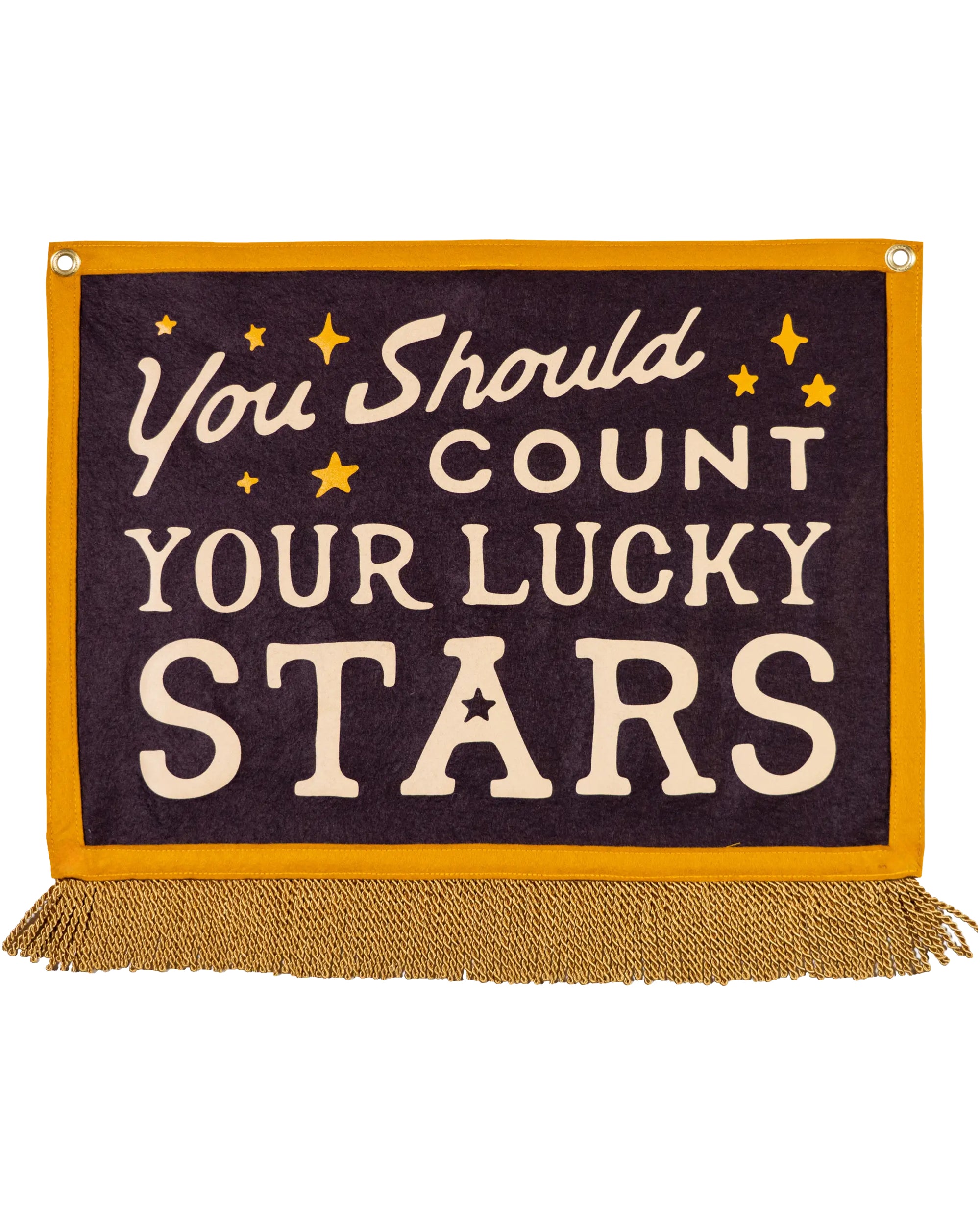 The Faire Count Your Lucky Stars Camp Flag is a dark purple handmade wall decor banner with gold trim, fringe, and cream text reading "You should count your lucky stars," accented by small yellow stars for a charming touch.
