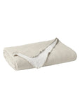 The Cozy Cotton Org. Blanket by Coyuchi Inc is a beige, reversible organic cotton chenille blanket with a soft, textured surface and white inner lining, shown partially turned over against a plain white background.
