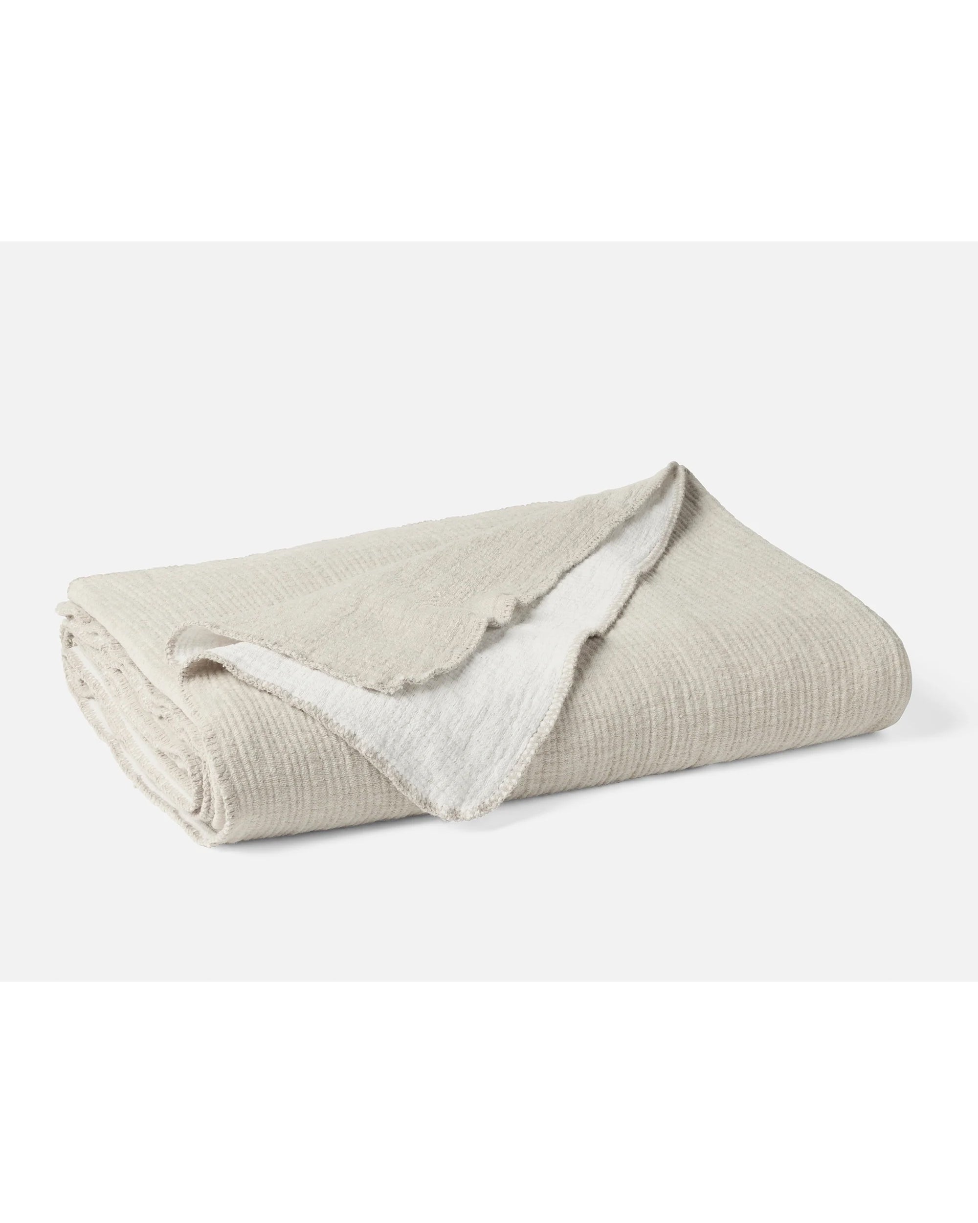 The Cozy Cotton Org. Blanket by Coyuchi Inc features a folded beige design with a soft, textured chenille outer layer and a white, plush inner lining, shown against a plain white background.