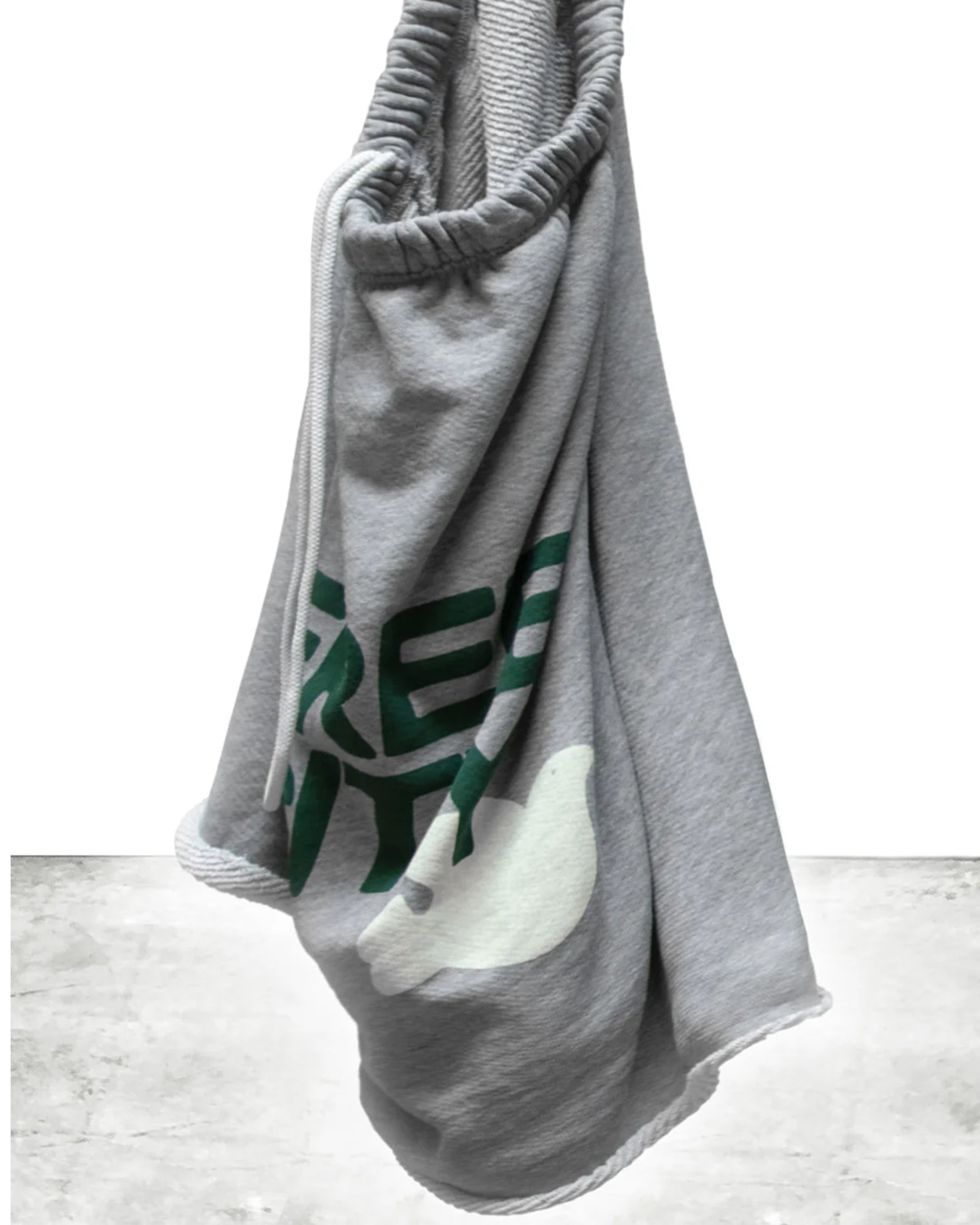The FreeCity Cutoffs by Free City (sparrow, LLC) is a light gray blanket in lightweight French terry with a white dove and partial green text, draped elegantly against a light background.