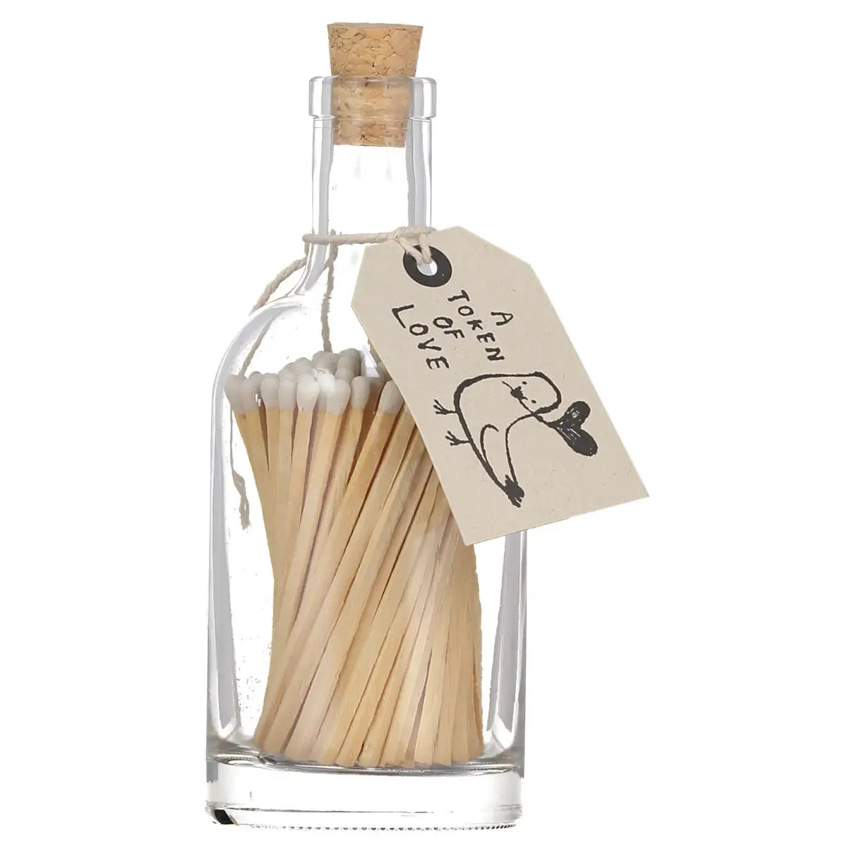 Faire&#39;s Glass Bottle Matches come in a plastic-free glass bottle sealed with a cork. A paper tag reading &quot;A TOKEN OF LOVE&quot; and a bird holding a heart makes them perfect for sustainable home décor.
