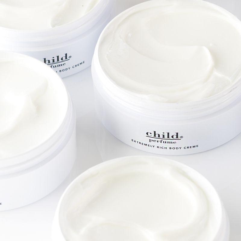 Open jars of Faire’s Child Rich Body Creme, filled with smooth, creamy white luxurious cream, are arranged close together on a white surface.