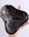 Triangular Mexican onyx and calcite bowl in dark chocolate hues, held by hand; Faire.