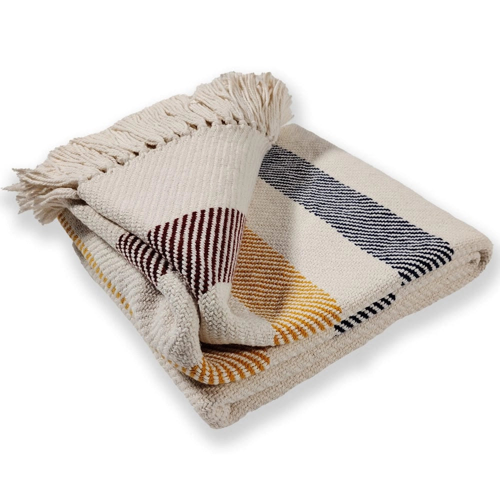 The Frontier Cotton Throw by Faire features brown, navy blue, and mustard yellow horizontal stripes with cream fringed edges on a cream background. Made from 100% cotton, it's shown folded against a white surface.