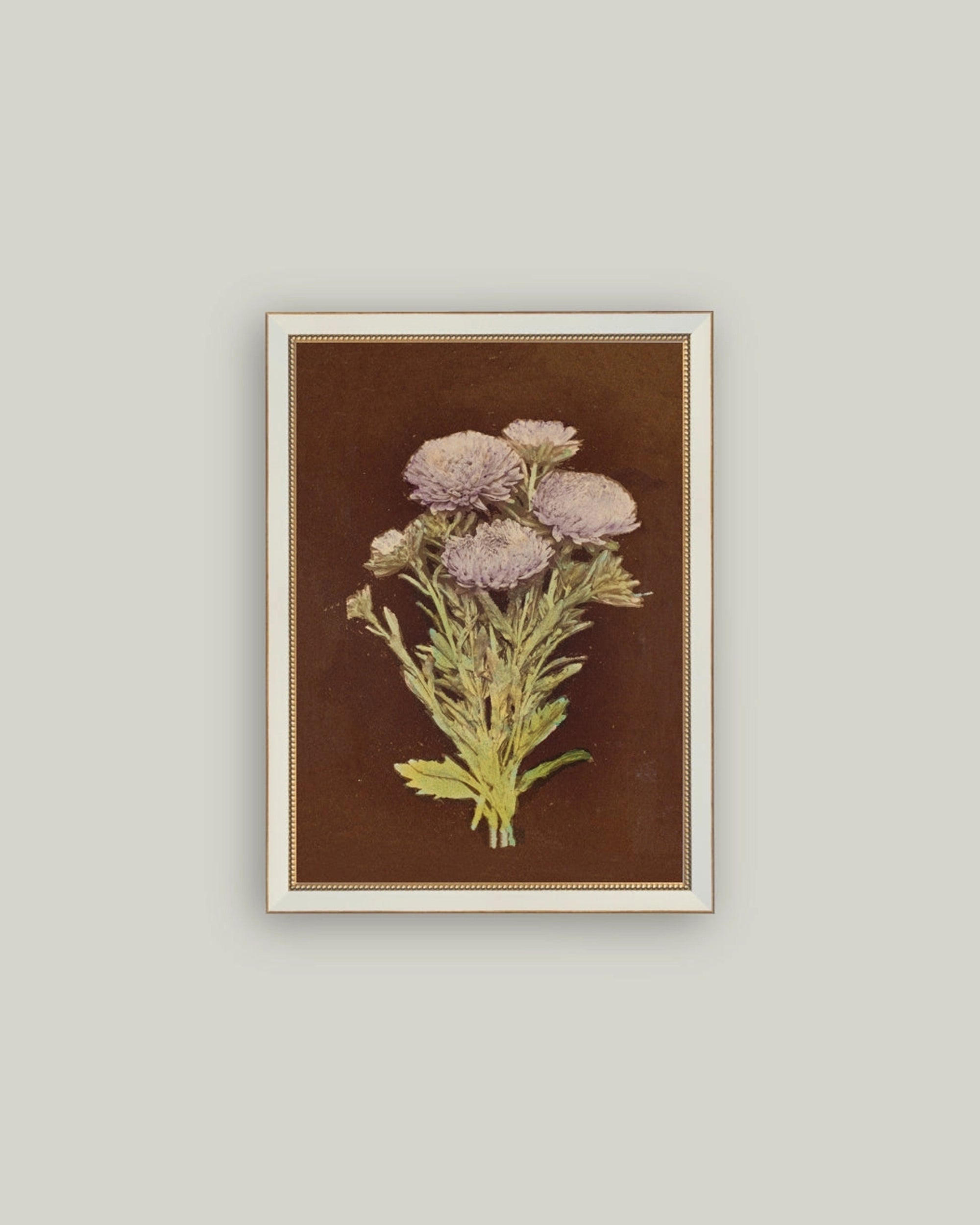 The "Lilac Dahlia On Brown" by Petal Lane Home features framed botanical art of lilac dahlias with green stems on a dark brown canvas, beautifully displayed on a light gray wall.
