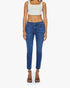 A person stands facing forward in a beige crop top and Mother’s Mid Rise Dazzler Ankle Fray blue jeans, paired with black heeled sandals, against a plain white background.