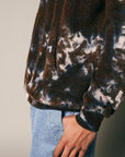 A person models the Riverside Tool & Dye Cashmere Hoodie in brown and white against a neutral background, wearing light blue jeans. Only their torso, part of one arm, and hand resting by their side are visible.