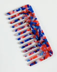 The Faire Hair Comb Assorted, featuring wide teeth and an anti-static design with a marbled red, blue, and white pattern, is shown on a plain white background.