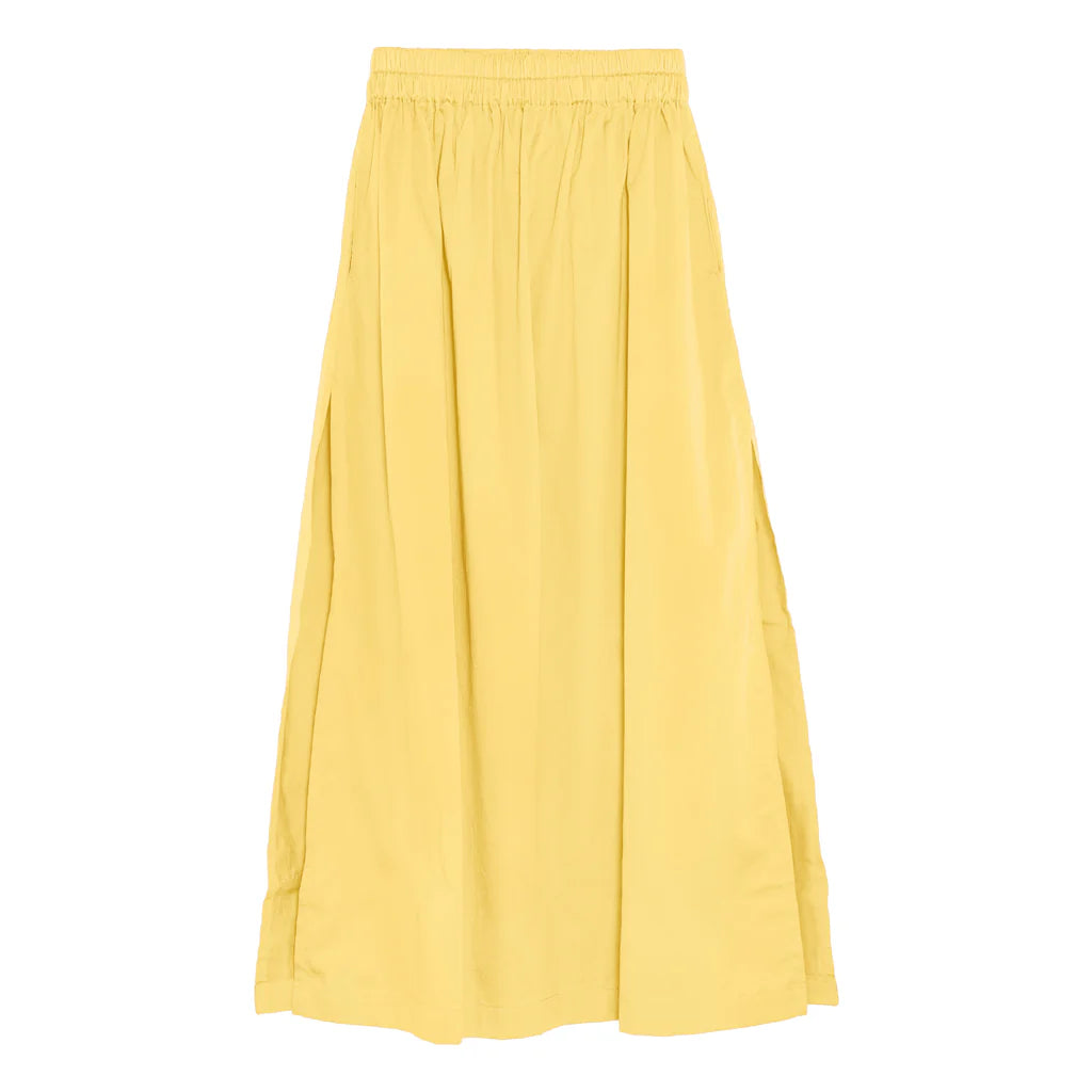 A flowy, ankle-length Delia Maxi Skirt by Mikoh in yellow with a high, elastic waistband and soft pleats. The lightweight fabric and modest high slits make it perfect for warm weather.