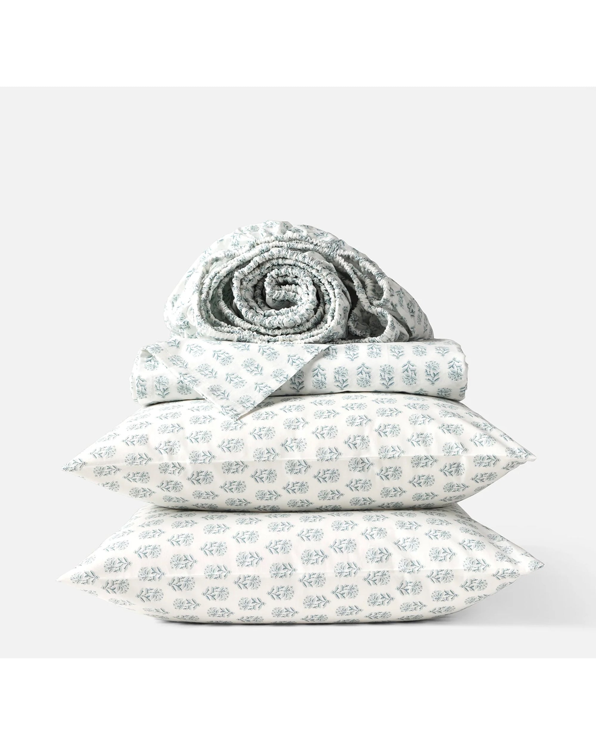 The Coyuchi Inc Org Percale Sheet Set Dew Chrysanthemum Queen features two pillows, a folded sheet, and a rolled blanket with light blue geometric floral patterns on white for a fresh, nature-inspired look.