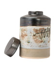 The Creative Co-op Ginger Jar is a hand-painted stoneware piece featuring earthy brown, beige, and white tones with abstract patterns and a glossy, reactive glaze on top. It comes with a round lid placed beside the jar.