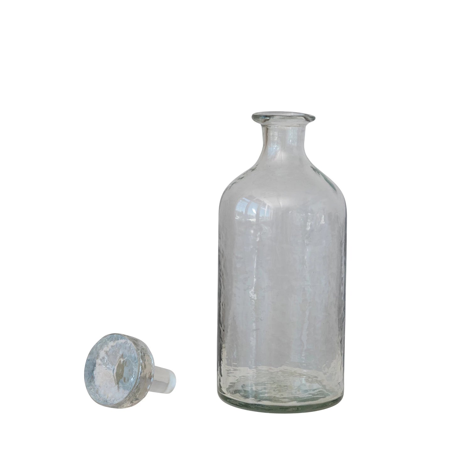 The Creative Co-op Decanter 20oz, a clear glass vessel with a narrow neck, stands upright beside its matching stopper on a plain white background—an elegant barware piece for the modern host.
