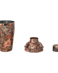 The Creative Co-op Stainless Steel Cocktail Shaker, a three-piece 16 oz set with a mottled oxidized copper finish, is shown disassembled into a large cup, strainer lid, and small cap, side by side on a white background.