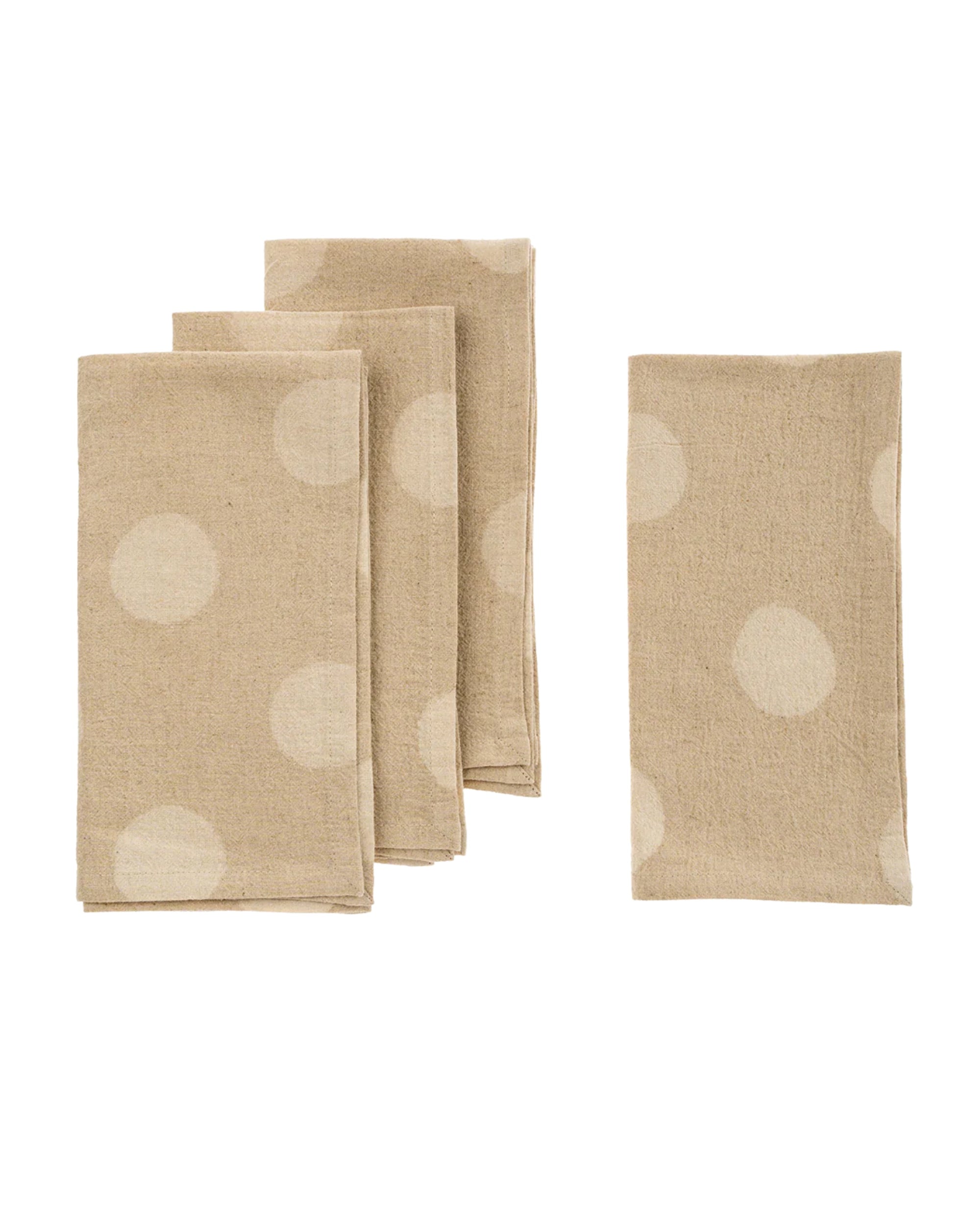The Indaba 4-7124 Dottie Resist Napkins S/4 features four beige linen napkins with bold white polka dots, styled three stacked and one unfolded on a white background—chic table linens for any occasion.
