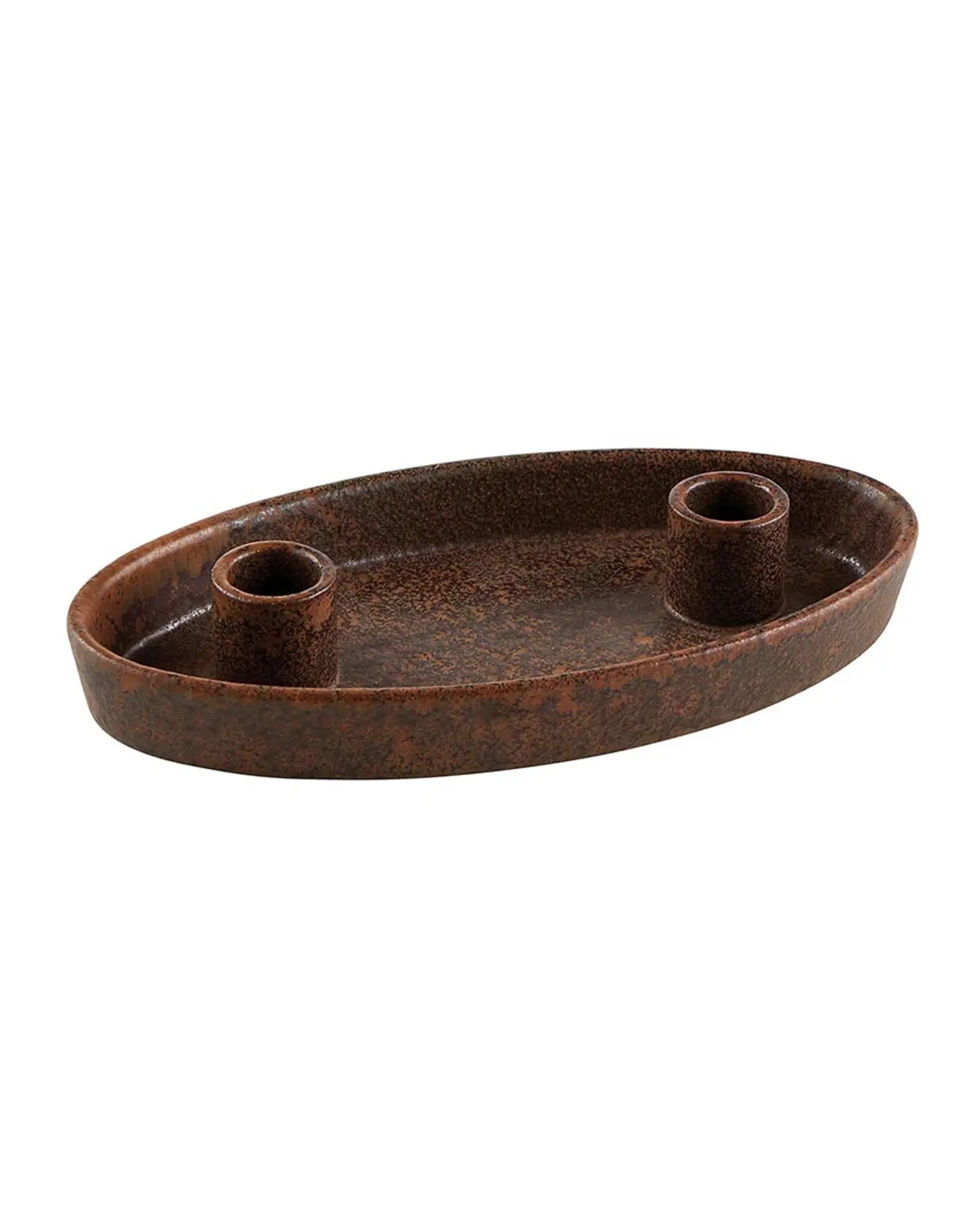 The Stone Double Taper by Faire is an oval ceramic tray with a brown textured finish and two cylindrical holders, offering a minimalist and elegant way to display taper candles on any tabletop.