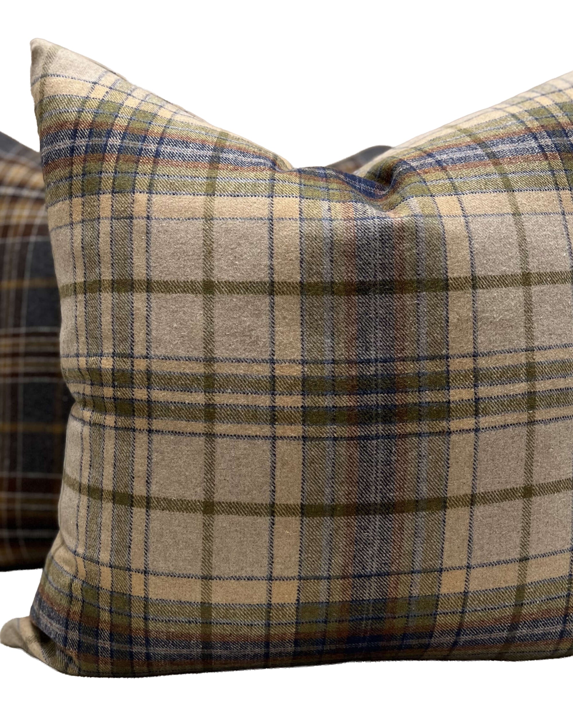 The Durrell Pillow 24X24 by TL At Home features a square shape with a beige, blue, and olive green wool plaid pattern on textured fabric. A second similar pillow is partially seen in the background.