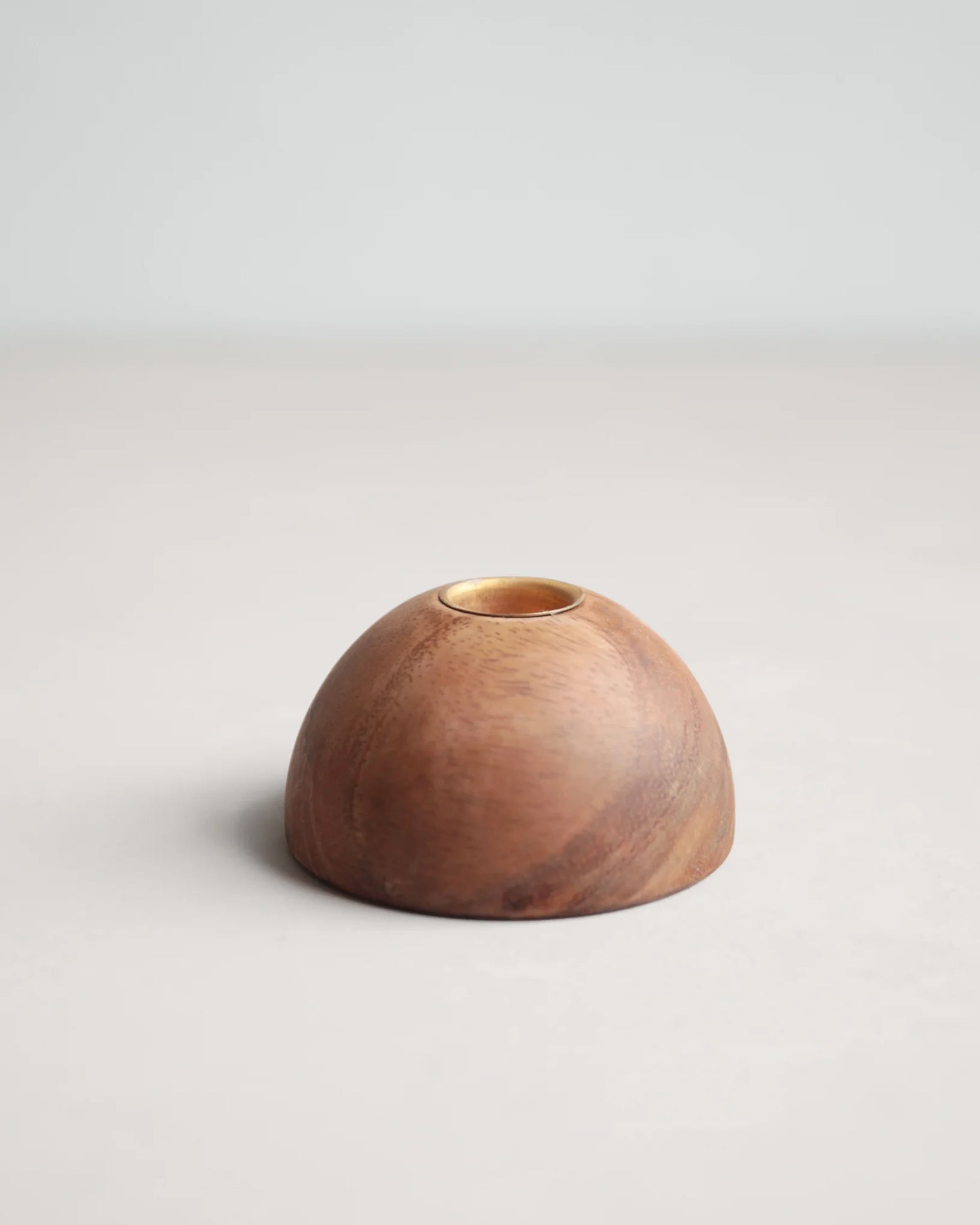 The Floral Society's Dusk Taper Holder is a small, dome-shaped handcrafted piece featuring a smooth finish and brass candle cups, displayed on a light, neutral surface with a plain background.