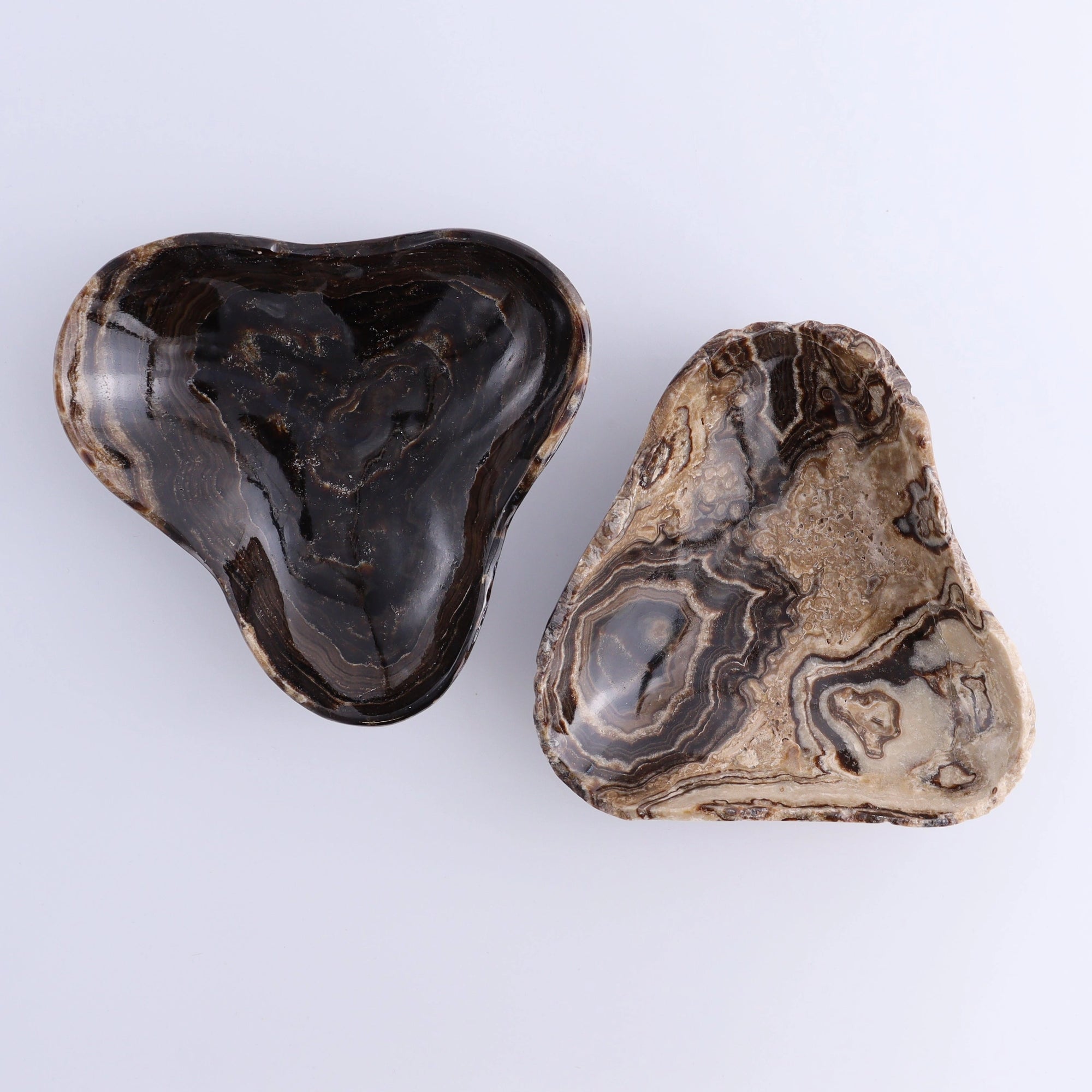 Heart stones beside a Mexican onyx chocolate triangular bowl with swirling patterns from Bungalow Furniture &amp; Accessories.
