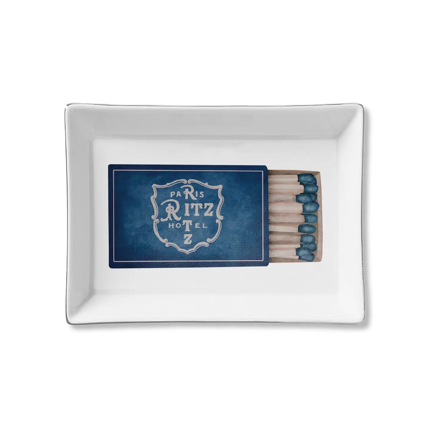 The Faire Ceramic Tray is a rectangular white ceramic trinket tray with a blue matchbook labeled "Paris Ritz Hotel" and matches on the right—ideal for organizing small items or giving as a stylish gift.