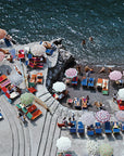 Enjoy a vibrant, midcentury beach scene with the Pieceworks Puzzle 1000 by Faire—featuring colorful umbrellas, lounge chairs, sunbathers on a terrace, and swimmers in crystal-clear blue water.