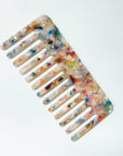 The Faire Hair Comb Assorted is a wide-tooth, anti-static comb made of translucent material with a vibrant marbled pattern in orange, blue, pink, and white, shown on a plain white background.