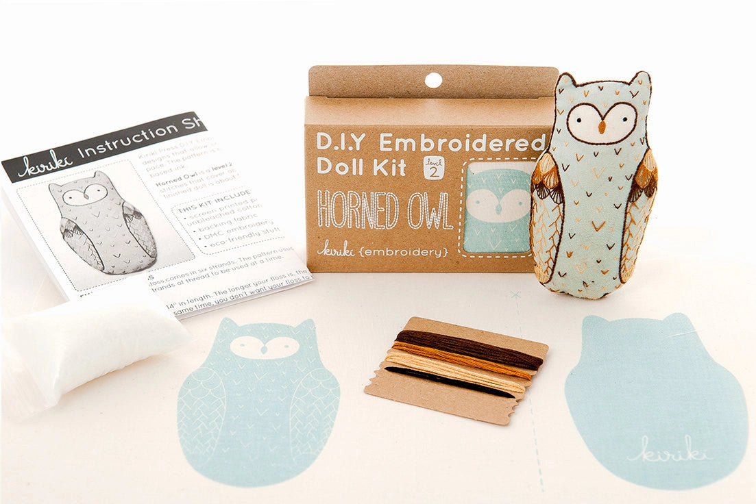 The Faire Horned Owl Embroidery Kit includes owl-patterned fabric, embroidery floss, stuffing, an instruction sheet, and a finished embroidered owl doll—everything you need to create your own horned owl design.