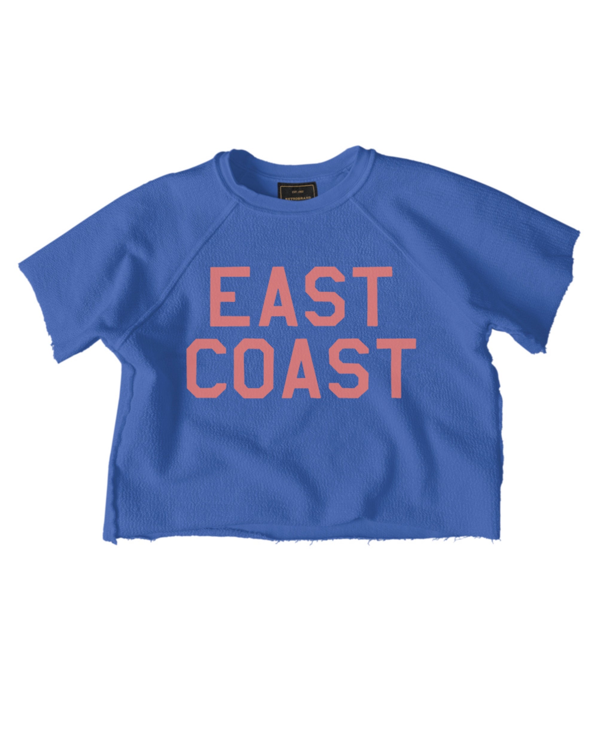The EAST COAST Sweatshirt by Wildcat Retro Brands is a blue short-sleeve tee with raw edges, inspired by vintage French terry and features bold pink "EAST COAST" lettering on the front.