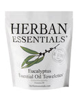 A white packaging bag labeled "Herban Essentials" with an illustration of eucalyptus leaves. The bag contains "Essential Oil Towelettes" and text reads: "Aromatherapeutic," "Contains 20," and "herbanessentials.com." Additional text highlights the all-natural benefits of these towelettes.