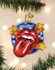 An Old World Ornaments piece by Faire hangs on a tree, displaying the Rolling Stones’ iconic red tongue logo with shooting stars and white-starred blue background, adding to a festive assortment of ornaments.