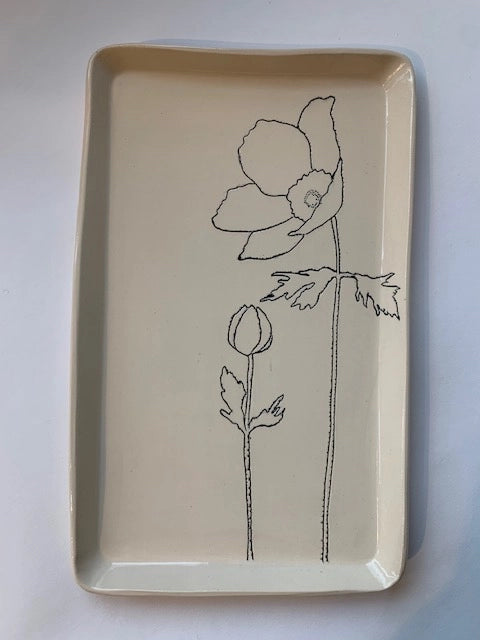 The CSF Tray by Faire is a rectangular cream ceramic tray featuring a minimalist black line drawing of two poppy flowers—one blooming, one budding—perfect for adding serene charm to any space.