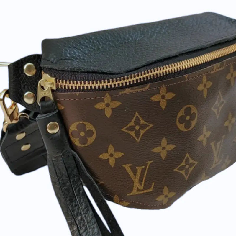 The Faire Upcycled Belt Bag features brown canvas with a classic monogram pattern, gold zipper, black leather accents, and a black leather strap.