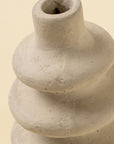 Close-up of the Ripple Paper Mache Bud Vase by Indaba, featuring a beige, textured, rounded tiered design with a narrow opening—ideal sustainable decor for any space.