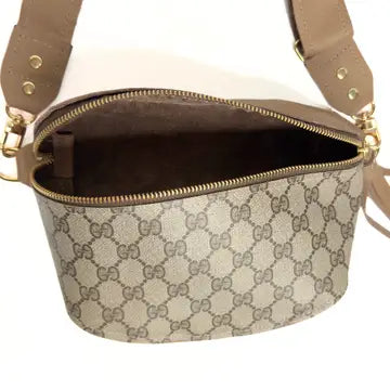 A black leather Faire Britt Belt Bag featuring a sleek design and adjustable strap, shown open to reveal its spacious interior—a timeless designer accessory for any collection.