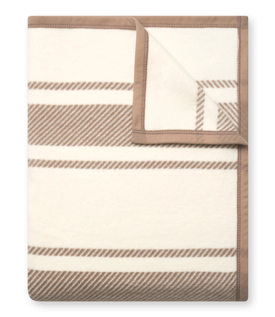 The Faire Dockside Stripe Blanket features wide light brown stripes on a cream base with solid light brown edging—one corner flipped to showcase the reverse—making it a stylish addition for coastal chic vibes in any room.