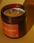 Gold Dust Woman Candle by Faire with gold-flecked wax, casting soft shadows on a yellow tabletop.