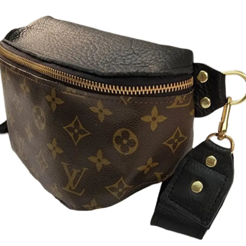 The Faire Upcycled Belt Bag features brown canvas with a monogram pattern, gold zipper, black adjustable strap with gold hardware and snap buttons.