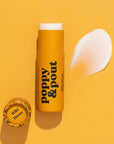 A yellow tube of Faire Poppy & Pout Lip Balm is displayed on a yellow background, its matching cap beside it and a smear of the balm to the right.