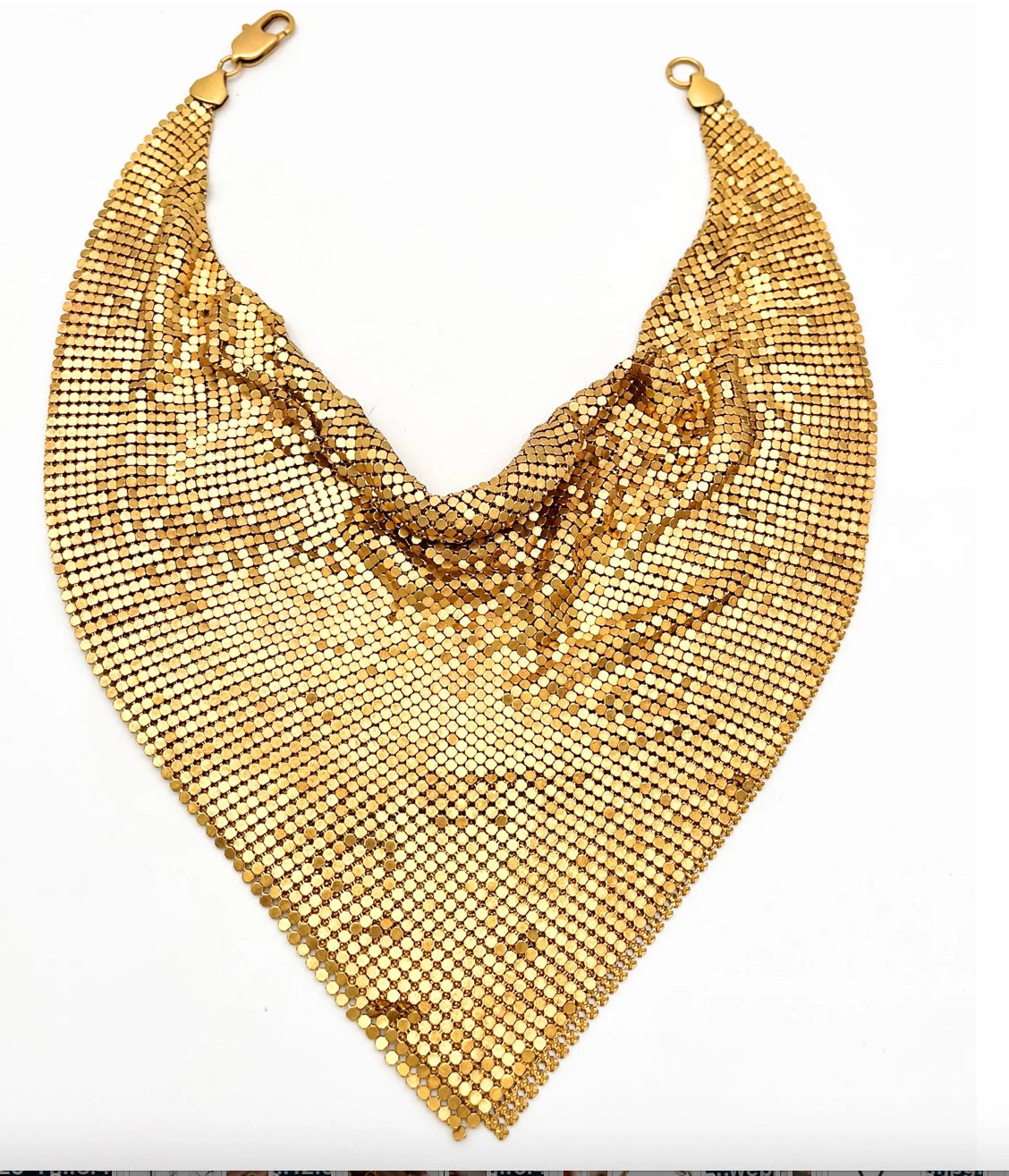 Displayed on a white background, the Faire Chain Mail Bandana Scarf Necklace features a shiny gold, triangular chain mail design with a draped style and clasps at each end, creating a bold vintage-inspired statement piece.