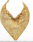 Displayed on a white background, the Faire Chain Mail Bandana Scarf Necklace features a shiny gold, triangular chain mail design with a draped style and clasps at each end, creating a bold vintage-inspired statement piece.