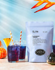 A package of Smith Tea by Faire sits on a table with three glasses of refreshing iced tea. Each drink is served with striped straws, garnished with blackberries and ice, against a backdrop of fresh oranges and hibiscus flowers.