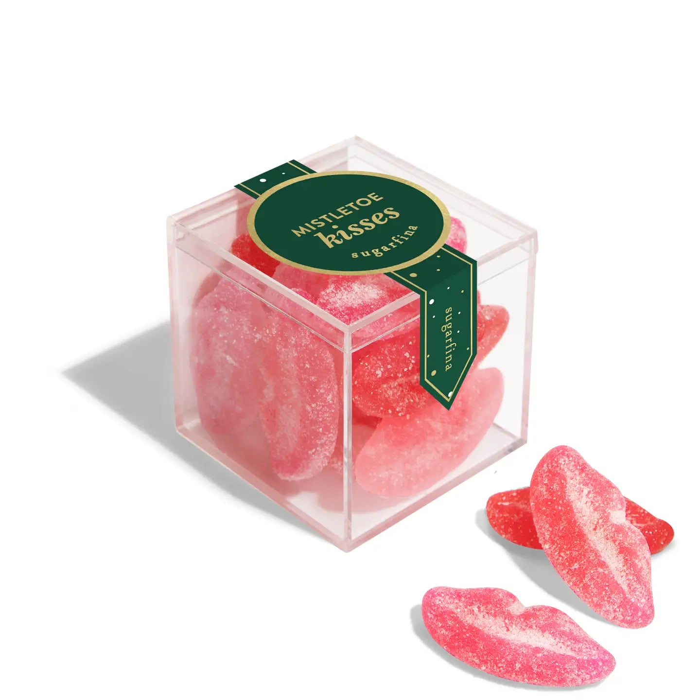 The Faire Christmas Candy Cube showcases pink, sugar-coated gummy lips as festive holiday treats. Two gummies sit outside the clear, branded box for a charming seasonal display.