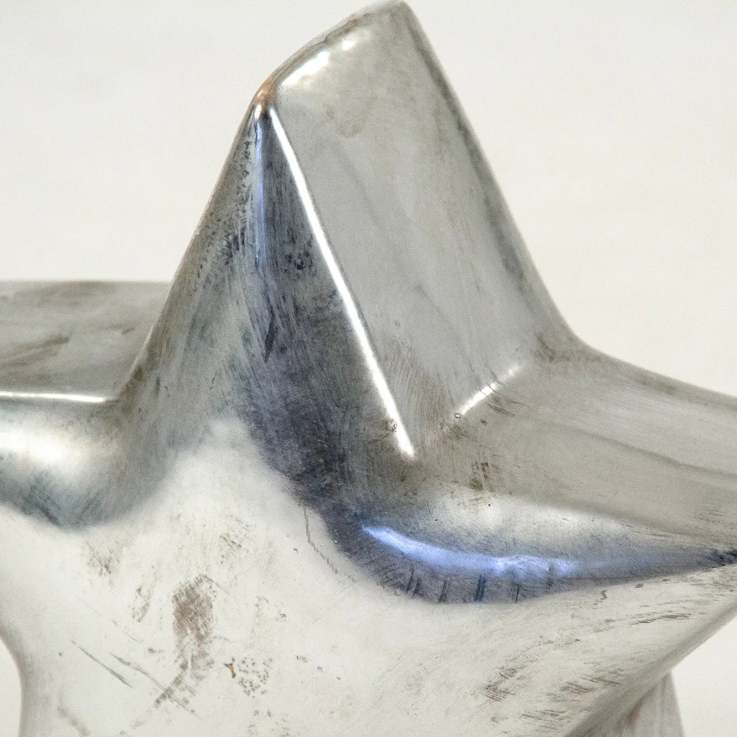 The Zentique Distressed Metallic Star features a shiny, five-pointed design with unique scratches and scuff marks, making it a standout decorative piece against a plain light background.