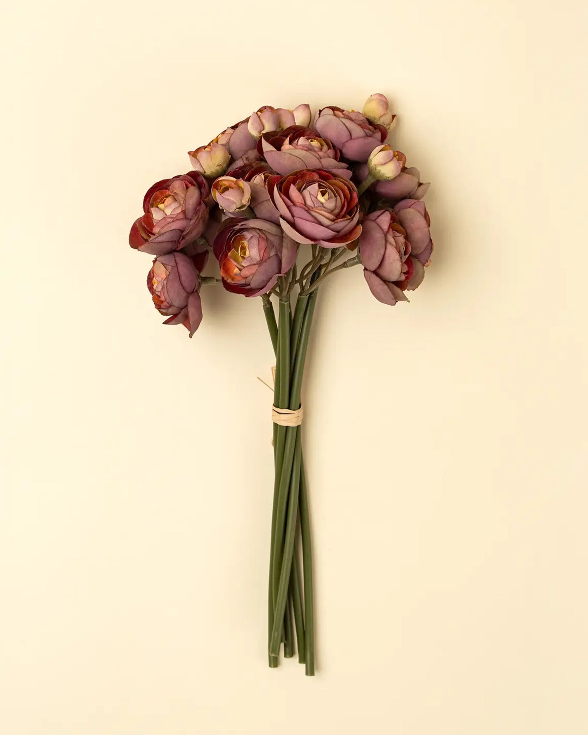 The Faire Ranunculus Flower features vibrant purple blooms with green stems, arranged against a plain beige background—ideal for display in decorative vases.