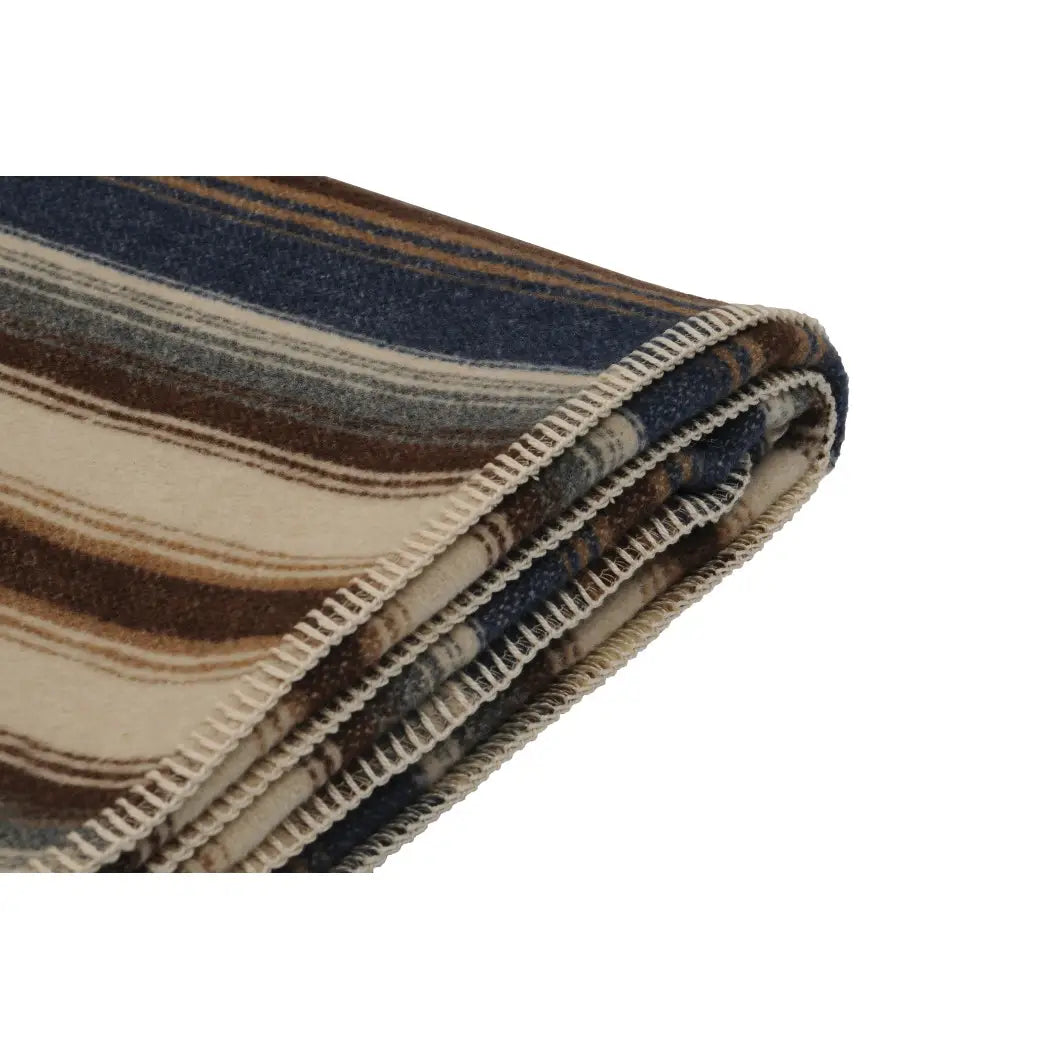 The Faire Cadillac Ranch Throw is a folded wool blanket with stitched edges, featuring horizontal stripes in blue, brown, beige, and cream. It's machine washable for easy care.